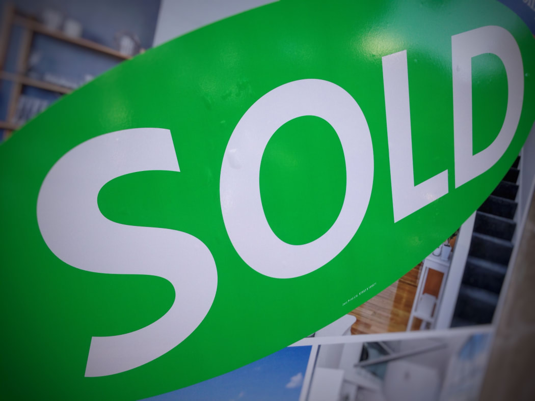 A sold sticker on a real estate sign outside a house in Auckland.