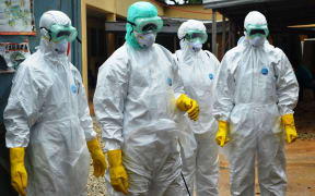 Health workers wearing protective suits prepare to carry the body of a victim of Ebola in Conakry, Guinea.
