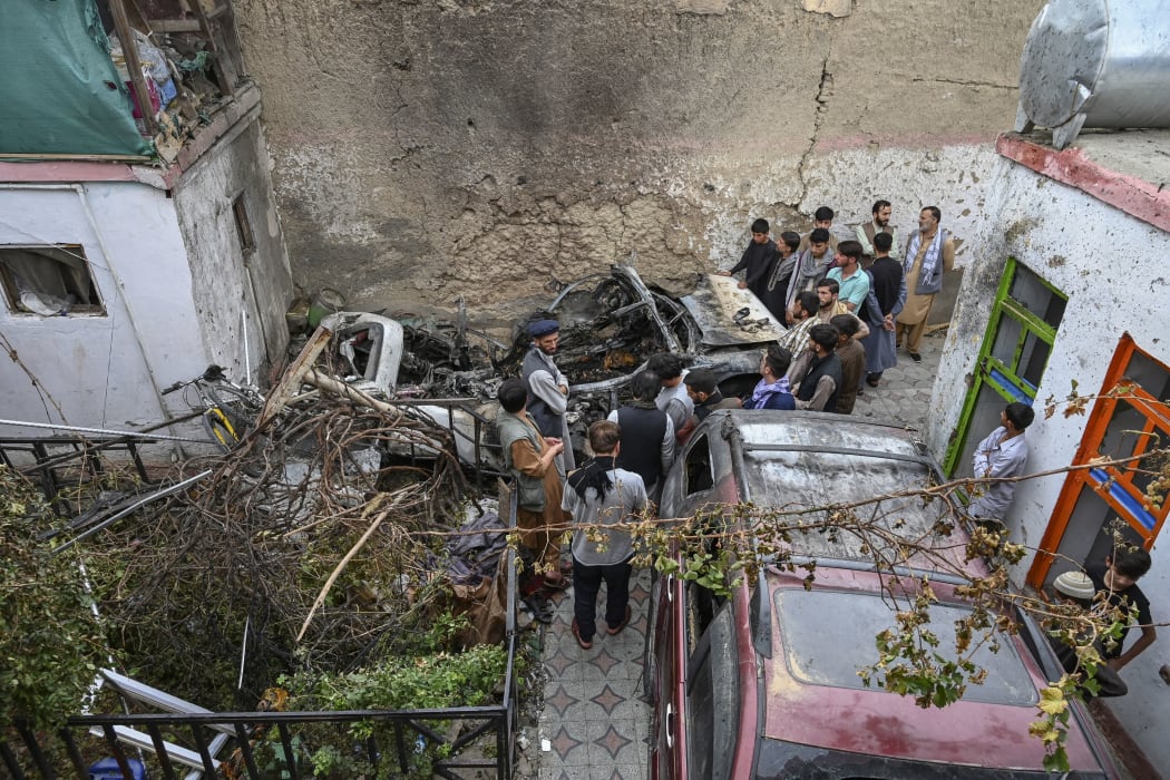 Afghan residents and family members of the victims gather next to a damaged vehicle a day after a US drone airstrike in Kabul on 30 August 2021.