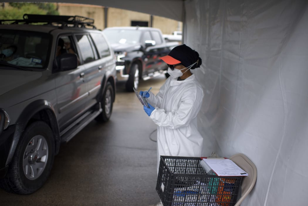 A healthcare worker takes information as cars line up at a Covid-19 testing site in Houston, Texas, 25 June 2020.