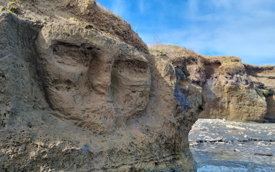 A skull carved into the sandstone cliffs at Waipipi Beach.