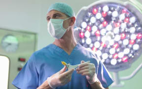 Orthopaedic surgeon in operating theatre with replacement hip stem (file)