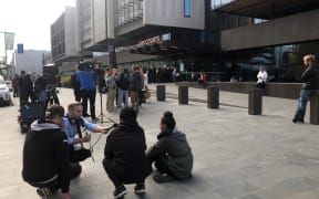 RNZ senior producer Justin Gregory (kneeling, with microphone) talks to victims families in front of the Justice Precinct in Christchurch.