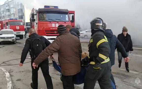 This photo taken from video released by the Russia Emergency Situations Ministry on December 30, 2023, shows people evacuating an injured person after shelling in Belgorod, about 30 kilometres (19 miles) from the border with Ukraine. Russia said on December 30, 2023, that a Ukrainian strike killed at least 14 people and injured 108 in the city of Belgorod. (Photo by Handout / Russian Emergencies Ministry / AFP) / RESTRICTED TO EDITORIAL USE - MANDATORY CREDIT "AFP PHOTO / Russian Emergencies Ministry / handout" - NO MARKETING NO ADVERTISING CAMPAIGNS - DISTRIBUTED AS A SERVICE TO CLIENTS