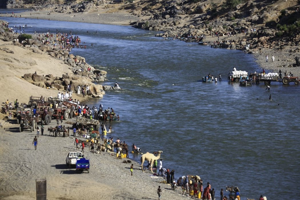 Ethiopian refugees who fled the fighting in the Tigray region gather on the banks of a border river with Sudan, in the Hamdayit area of Sudan's eastern Kassala state.