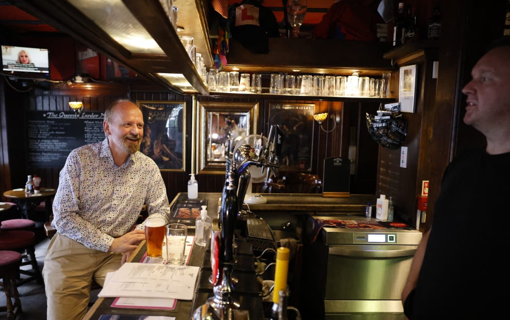 A customer drinks a pint standing at the bar of a pub in central London on July 19, 2021 as coronavirus restrictions are lifted.