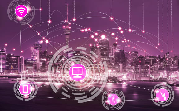 Smart city wireless communication network with graphic showing concept of internet of things ( IOT ) and information communication technology ( ICT ) against modern city buildings in the background.