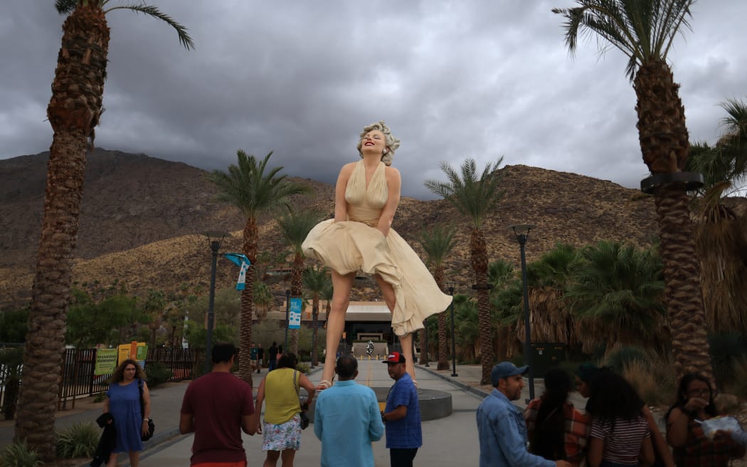 People visit the "Forever Marilyn" statue, designed by US artist John Seward Johnson II, framed by storm clouds as Hurricane Hilary heads north toward southern California, in Palm Springs, California, on August 19, 2023. Hilary brought heavy rains on August 19 to portions of Mexico's Baja California peninsula and the southwestern United States, as officials warned the powerful hurricane was likely to cause "catastrophic and life-threatening" flooding. (Photo by DAVID SWANSON / AFP) / RESTRICTED TO EDITORIAL USE - MANDATORY MENTION OF THE ARTIST UPON PUBLICATION - TO ILLUSTRATE THE EVENT AS SPECIFIED IN THE CAPTION