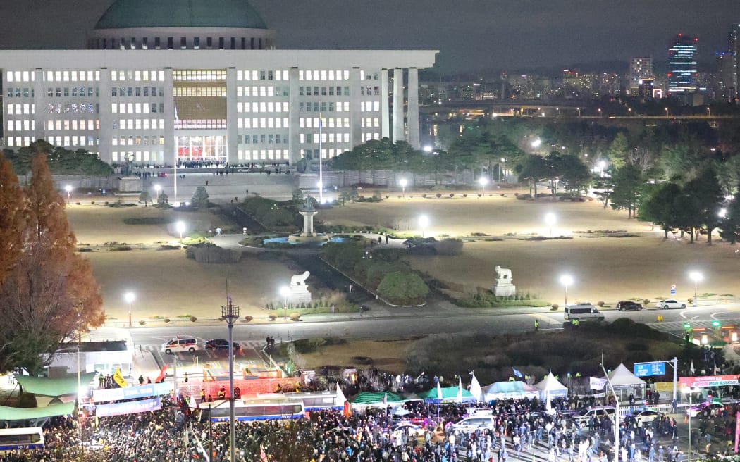 People gather outside the National Assembly in Seoul on December 4, 2024, after South Korea President Yoon Suk Yeol declared martial law. - South Korea's President Yoon Suk Yeol on December 3, declared martial law, accusing the opposition of being "anti-state forces" and saying he was acting to protect the country from "threats" posed by the North. (Photo by YONHAP / AFP) / - South Korea OUT / NO USE AFTER JANUARY 3, 2025 15:00:00 GMT -  - SOUTH KOREA OUT / NO ARCHIVES -  RESTRICTED TO SUBSCRIPTION USE