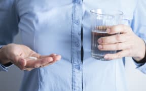 Woman taking medication with a glass of water. (Photo by CRISTINA PEDRAZZINI/SCIENCE PHOT / CPD / Science Photo Library via AFP)