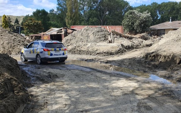 Police patrol between banks of silt in a small gathering of now-trashed homes by the Esk River on 22 February.