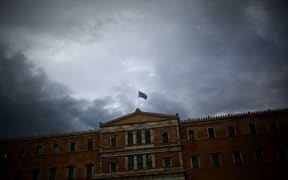 A Greek flag waves at the top of the Greek Parliament.