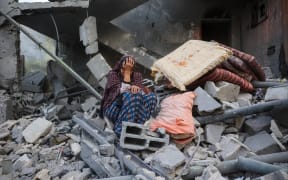 A woman cries while sitting on the rubble of her house, destroyed in an Israeli strike, in the Nuseirat refugee camp in central Gaza Strip on 18 March, 2025. Israel on March 18 unleashed its most intense strikes on the Gaza Strip since a January ceasefire, with rescuers reporting 220 people killed, and Hamas accusing Benjamin Netanyahu of deciding to "resume war" after a deadlock on extending the truce.