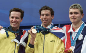 Gold medalist Grant Hackett of Australia (C) is flanked by his compatriot Kieren Perkins, who took the silver, and bronze medalist US Chris Thompson after the men's 1500m freestyle final, 23 September 2000 at Sydney International Aquatic center during the Sydney 2000 Olympic Games. AFP PHOTO GREG WOOD (Photo by GREG WOOD / AFP)