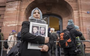 Syrian campaigner of the Caesar Families Association Yasmen Almashan holds pictures of victims of the Syrian regime as she and others wait outside the courthouse.