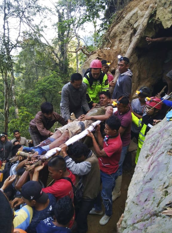 In this undated photo released by Indonesian Search And Rescue Agency (BASARNAS) rescuers evacuate a survivor from inside of a collapsed gold mine in Bolaang Mongondow, North Sulawesi, Indonesia.