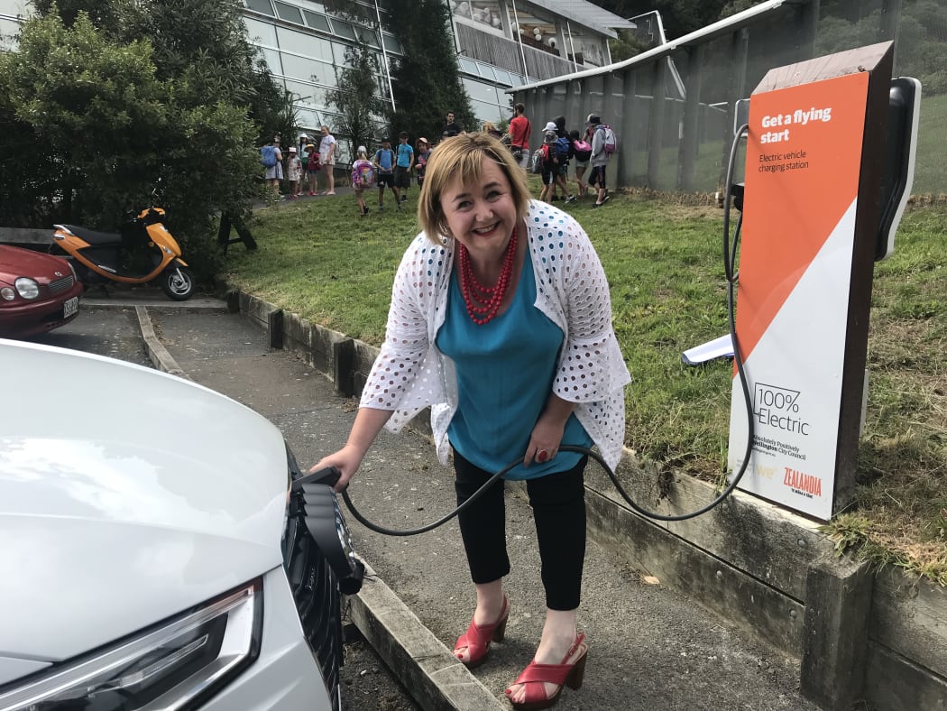 Megan Woods charging a hybrid electric car.