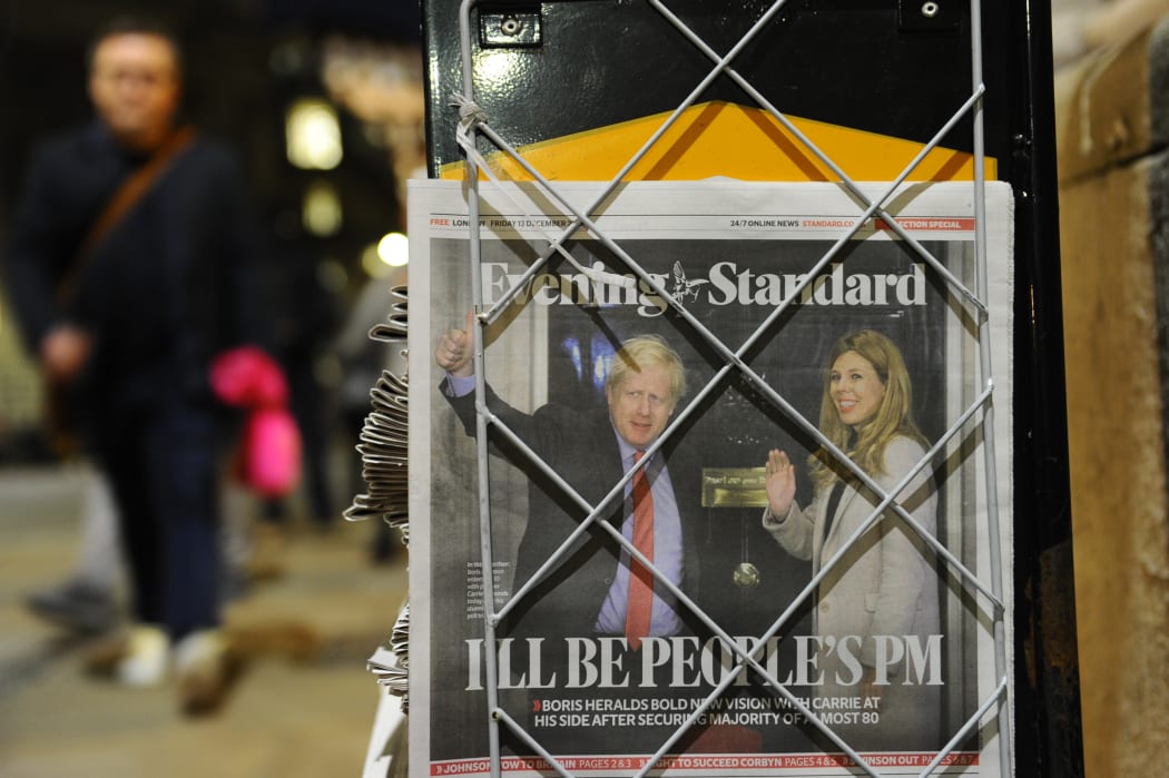 A pedestrian takes a copy of the London Evening Standard newspaper in London on December 14, 2019, with the front page reporting on the election victory of Prime Minister Boris Johnson's Conservative Party in the general election.