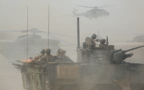 File photo taken on March 27, 2019 shows a French armoured vehicle driving by helicopters during the start of the French Barkhane Force operation in Mali's Gourma region.