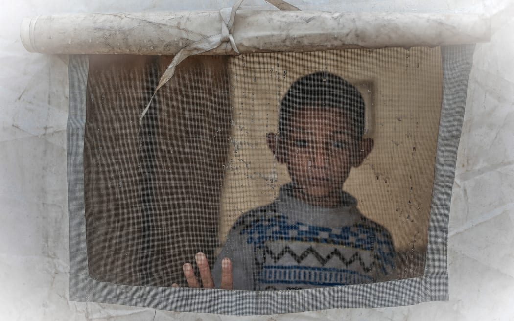 A boy looks out from a tent at a makeshift camp sheltering displaced Palestinians after heavy rains in the Zeitoun neighbourhood of Gaza City on 11 December, 2025.