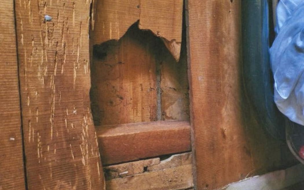 A hole in the wall between rooms showing no insulation.
