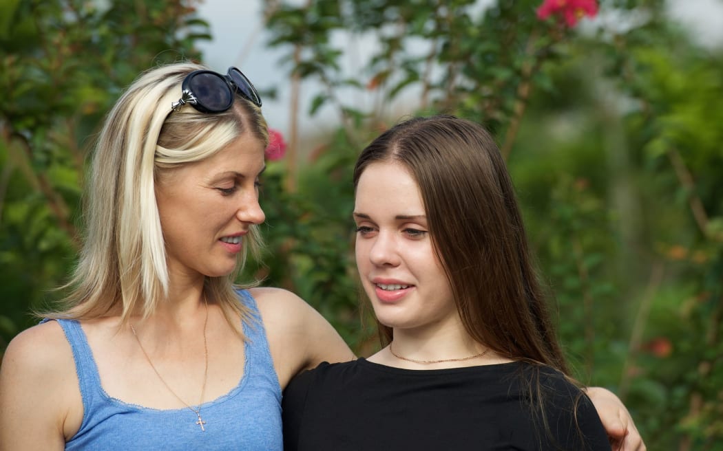 A photo of a mother and teenage daughter talking outdoors