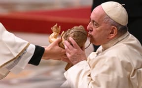 Pope Francis kisses a figurine of baby Jesus as he attends the Christmas Eve mass at The St Peter's Basilica in the Vatican on December 24, 2022. (Photo by Andreas SOLARO / AFP)