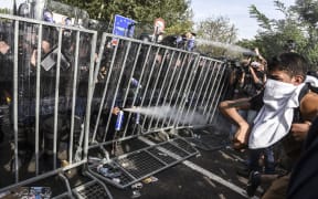 Hungarian riot police use pepper spray to push back refugees at the Hungarian border with Serbia.