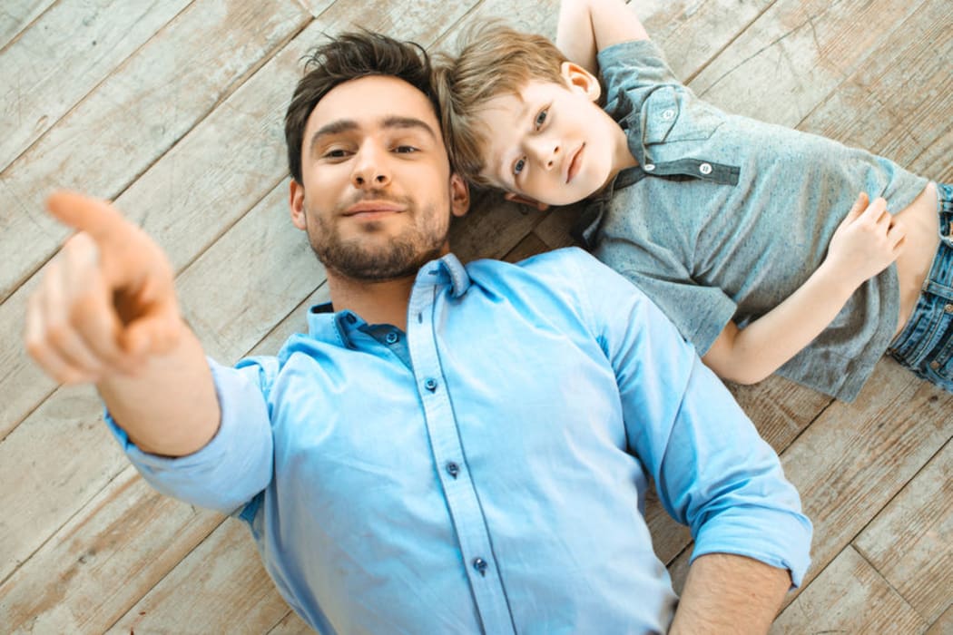 A photo of a father and son lying on the ground