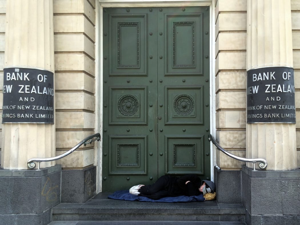a homeless person sleep on the steps of a bank in new zealand in 2015.