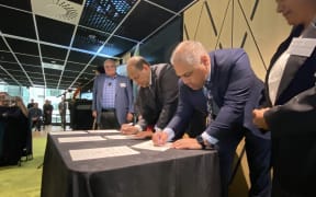 Associate Housing Minister Peeni Henare, foreground, signs a new housing agreement.