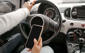 Woman hand hold and use mobile phone in personal auto. Close up view. Modern luxury automobile. Concept of driving car