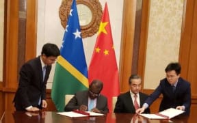 Jeremiah Manele and Wang Yi signing the communique.
