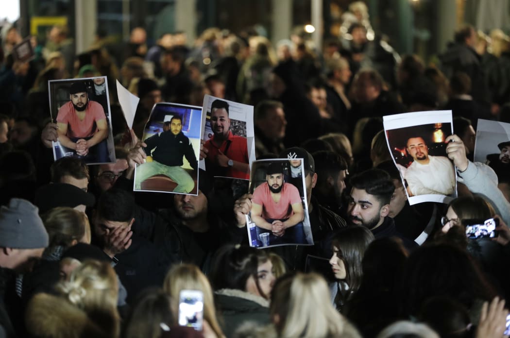 Mourners hold up photos, believed to be of vicitims, during a vigil close to a crime scene in Hanau, near Frankfurt.