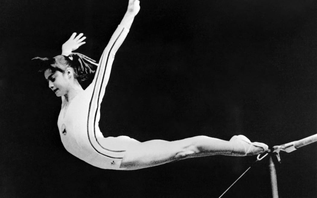(FILES) In this file photo taken on July 17, 1976 Romanian Nadia Comaneci executes her final jump on the uneven bars during the team compulsory portion of the competition during the Montreal Olympic Games. Behind the glamour and success, beatings and humiliation: a new book about Romania's legendary gymnast Nadia Comaneci has used the archives of the feared communist-era Securitate secret police to reveal the abuse she suffered even while being feted for her sporting glories. (Photo by STAFF / DPA / AFP)