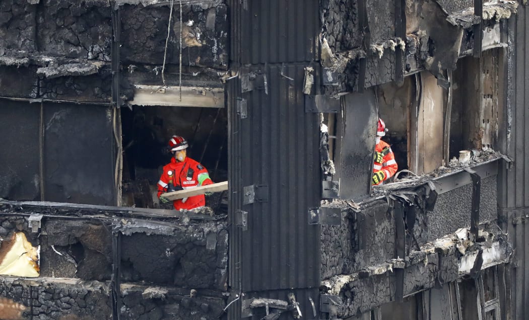 Members of the emergency services work on the middle floors of the charred remains of the Grenfell Tower block.