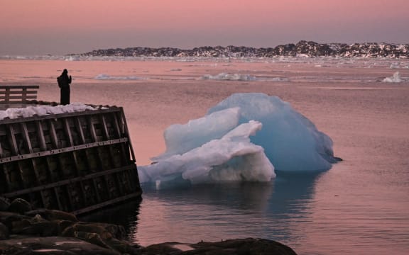 A woman takes a photo of an ice block at the harbour in Nuuk, Greenland, on January 29, 2026. (Photo by Ina FASSBENDER / AFP)