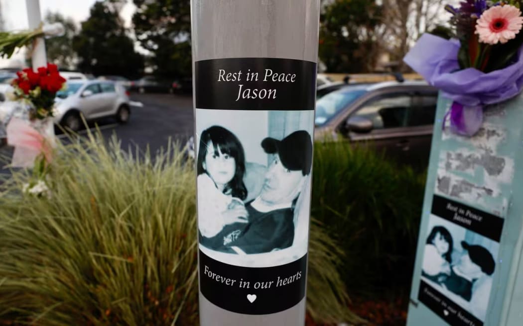 Floral tributes and posters laid at the scene on New North Rd where Jason McEwen was killed while walking his dog last year. Photo / Dean Purcell