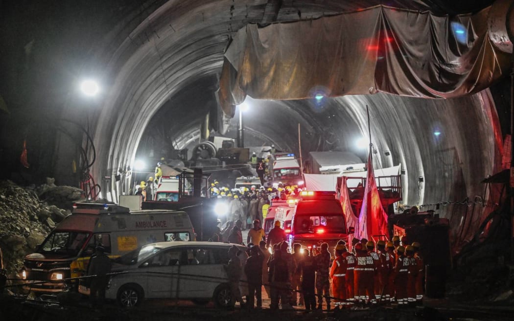 National Disaster Response Force (NDRF) personnel along with other rescue operatives gather at the entrance of the under construction Silkyara during a rescue operation for trapped workers after a section of the tunnel collapsed, in the Uttarkashi district of India's Uttarakhand state on November 28, 2023. Indian rescuers have safely brought out all 41 workers from a collapsed Himalayan road tunnel after a marathon 17-day engineering operation to free them, a minister said on November 28. (Photo by Sajjad HUSSAIN / AFP)