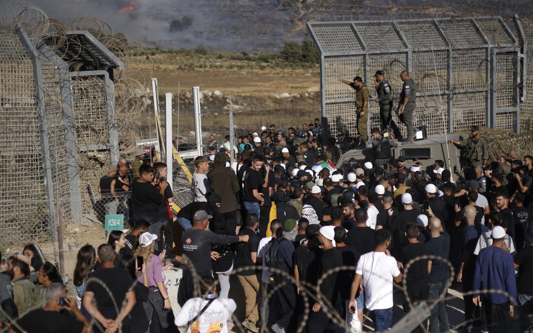 Members of the Druze community attempt to enter Syria through the buffer zone between Syria and the Israeli-annexed Golan Heights near Majdal Shams on July 16, 2025. Israeli troops on July 16 sought to control crowds and prevent Druze from crossing the border with Syria, after deadly violence in the country's south that prompted Damascus to send in government forces. (Photo by Jalaa MAREY / AFP)