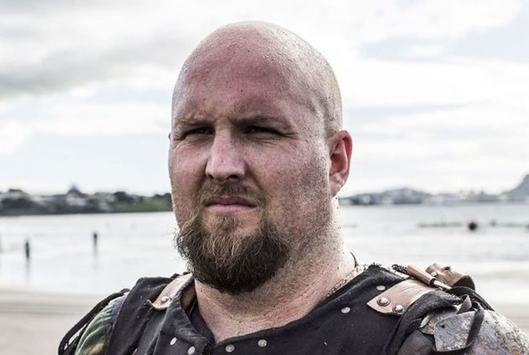 Martainn with a stern expression on a beach