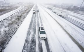 Traffic moves slowly along a snow-covered Highway 401 in London, Ontario, Canada, during a large winter storm on December 23, 2022. - Schools and some highways in the region were closed, and air travel was disrupted as the system made its way across the province. (Photo by Geoff Robins / AFP)