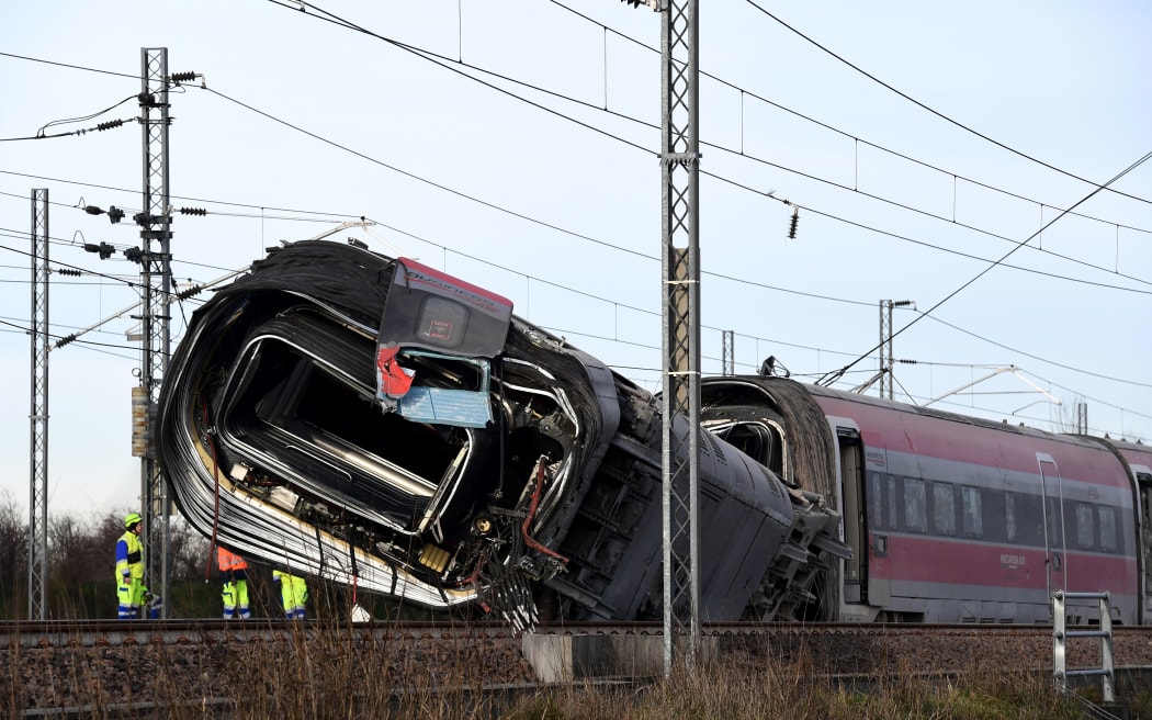Members of the rescue team gather in front of a damaged carriage on the site of a derailed train, outside the city of Lodi, near Milan, northern Italy. 6 February 2020.