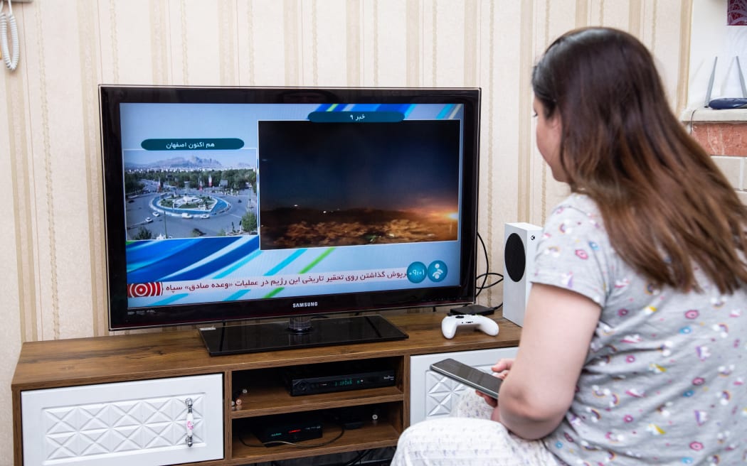 An Iranian Woman watches an Iranian news TV channel in Tehran, Iran after Iranian official TV confirms 'massive explosions' in central Isfahan province, as US officials confirm Israel carried out strike inside Iran, on April 19, 2024. (Photo by Hossein Beris / Middle East Images / Middle East Images via AFP)