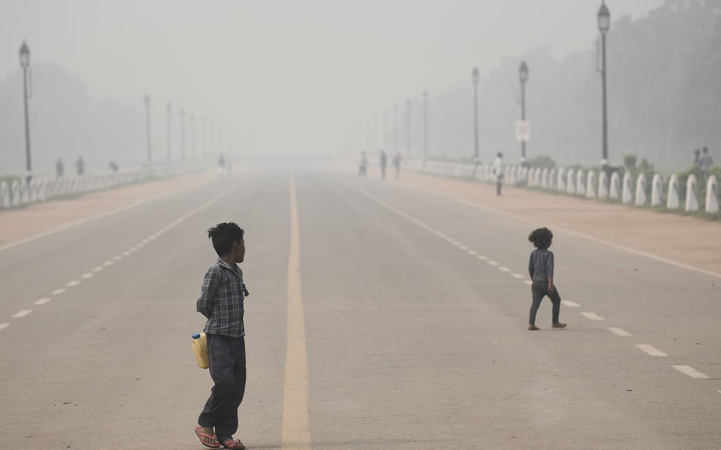 Children walk along Rajpath near India Gate under heavy smog conditions in New Delhi on November 9, 2020. (Photo by Sajjad HUSSAIN / AFP)