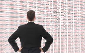 A Man in front of a big screen with numbers