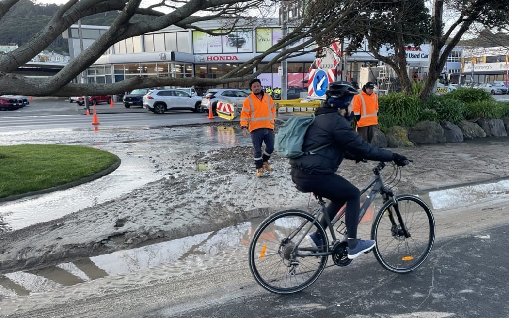 Cyclists ride through layers of slick silt as contractors put traffic management in place about a broken water main effecting Kent and Cambridge Terraces in central Wellington.