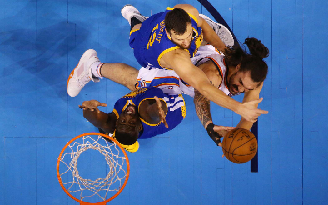 Oklahoma City Thunder forward Steven Adams shoots as he's swarmed by two Golden State Warriors players.