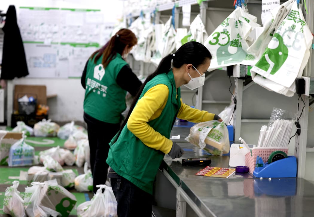 Staff members of the online grocery platform Meituan Maicai sort and pack ordered groceries in east China's Shanghai, April 12, 2022.