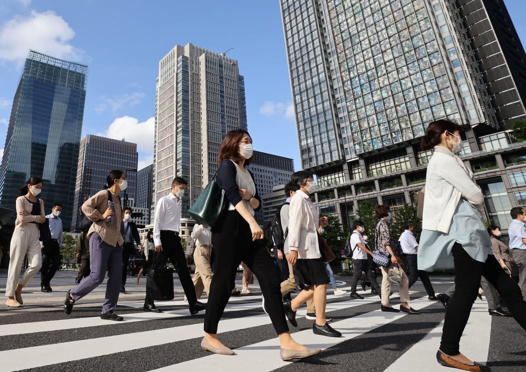 People wearing face masks are seen during commuting hour under a refreshing clear blue sky in front of Tokyo Station in Chiyoda Ward, Tokyo.